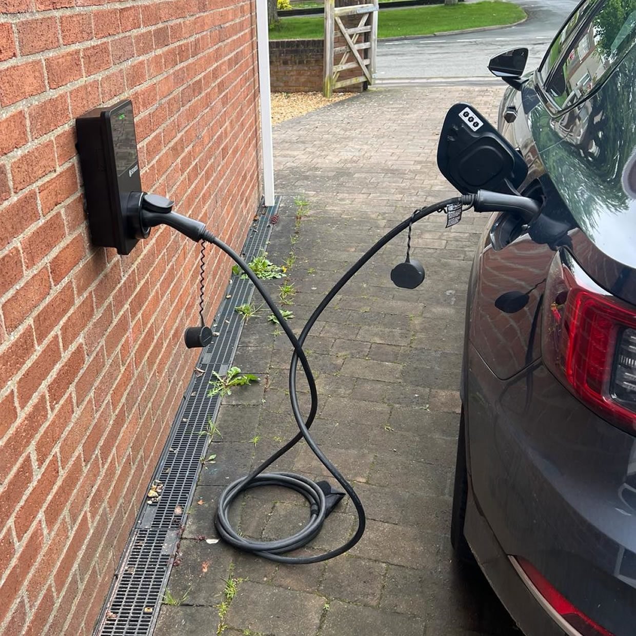 Homeowner charging their electric vehicle in the driveway using a home EV charging station.