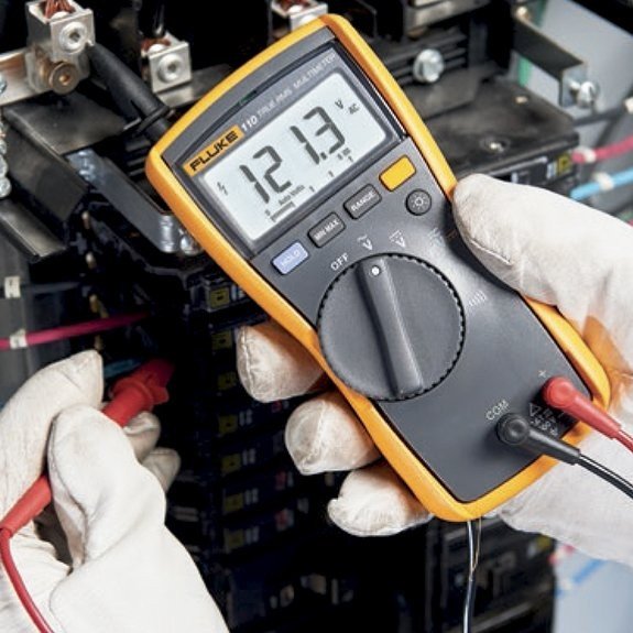 Electrician using a multimeter to troubleshoot electrical wiring.
