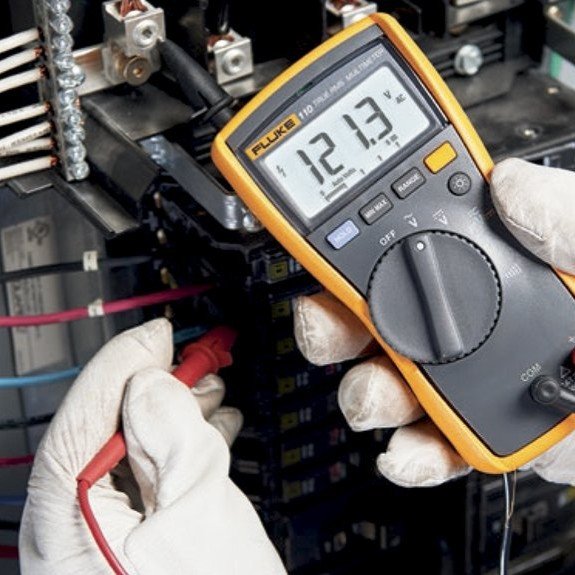 Electrician troubleshooting an electrical panel with a multimeter to diagnose wiring or breaker issues.