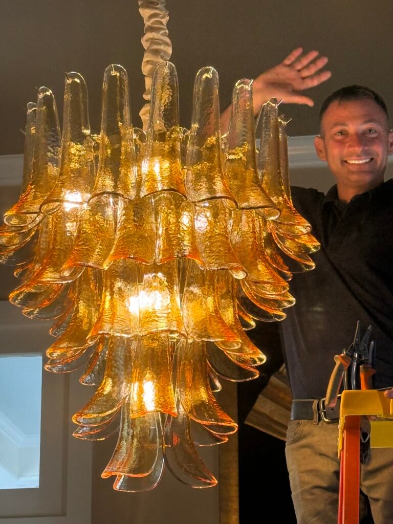 Sheep Electrical owner Jeffrey Mouton installing a large amber glass chandelier