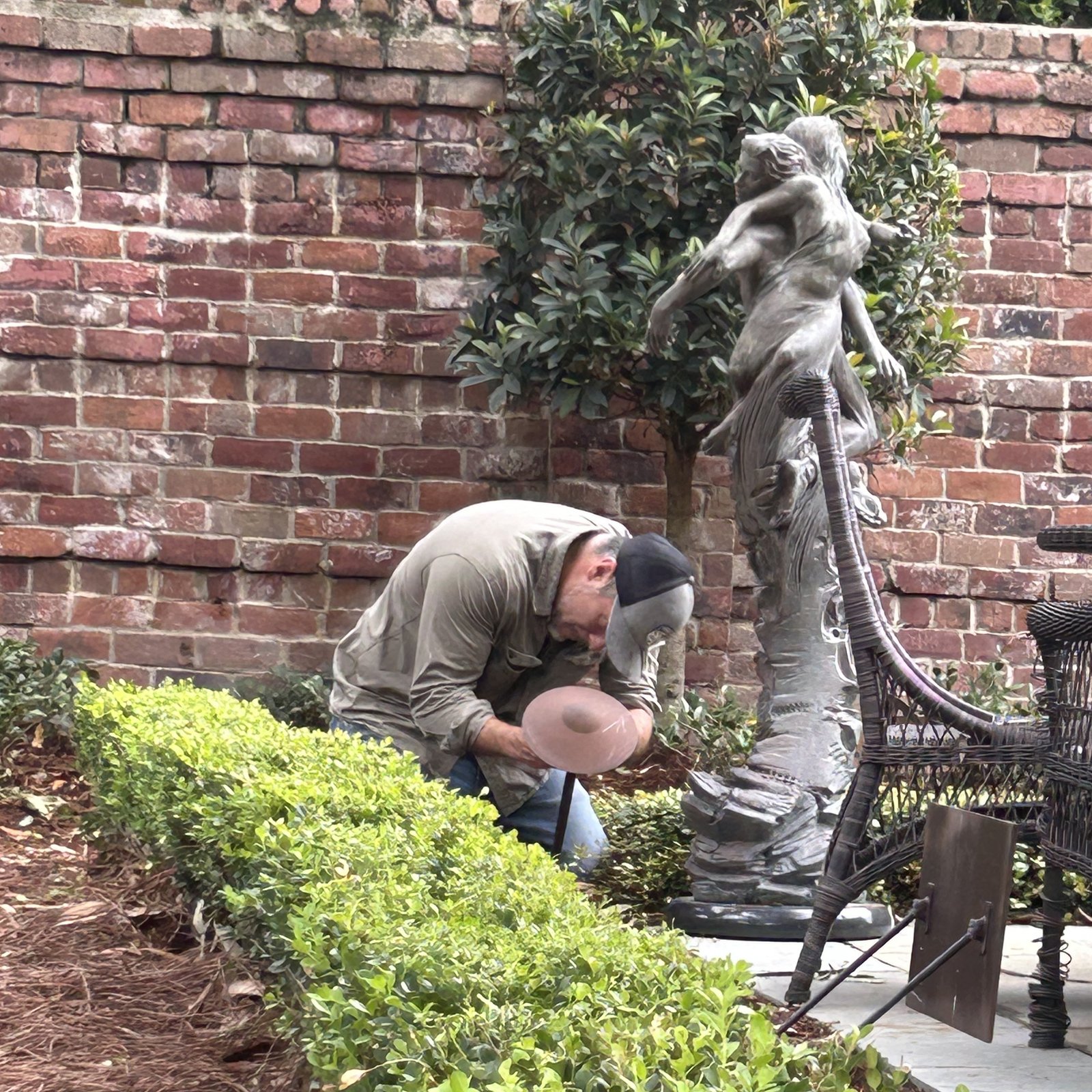 Sheep Electrical technician Kirk servicing outdoor landscape lighting beside a garden sculpture