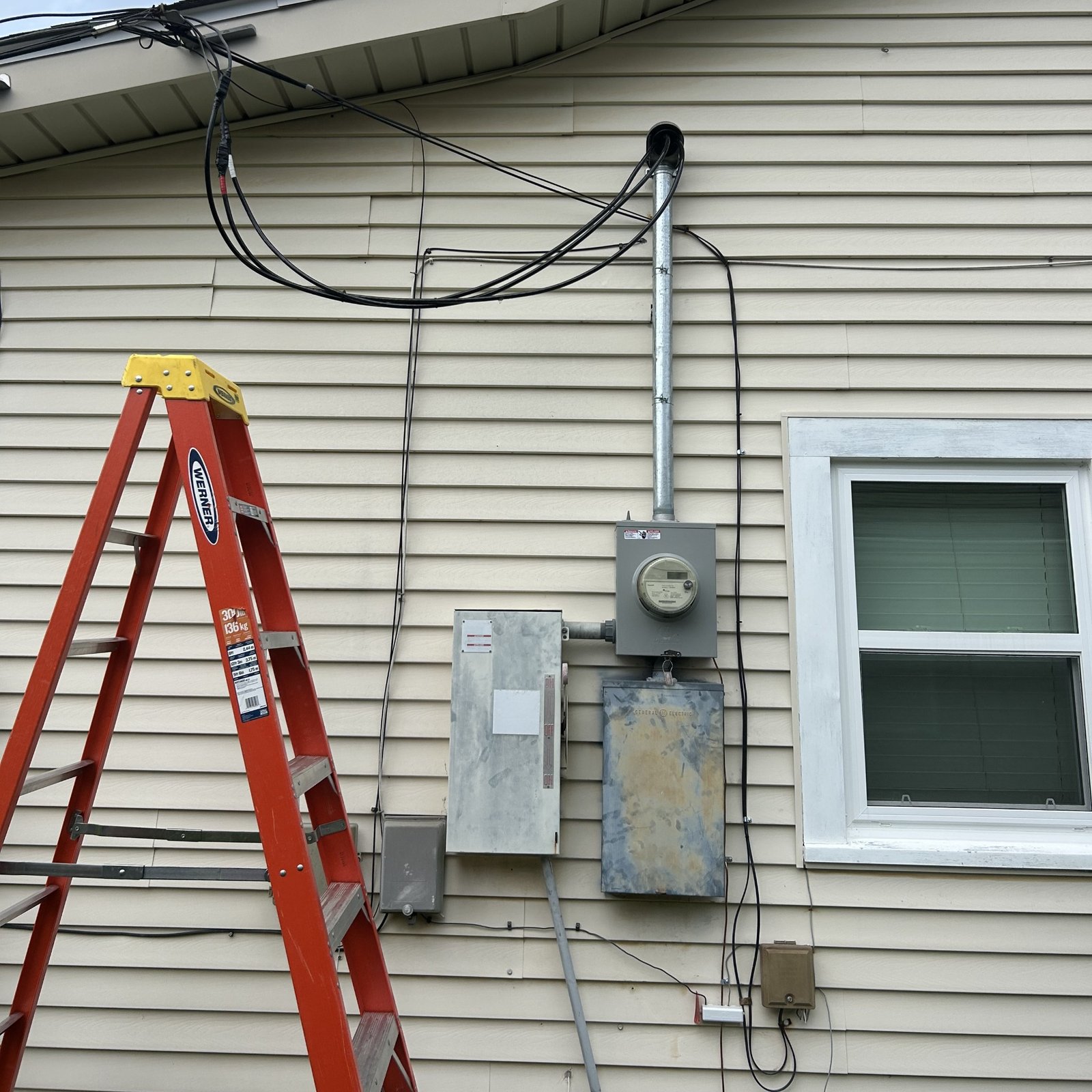 Exterior electrical meter, service riser and enclosures during a residential service upgrade.